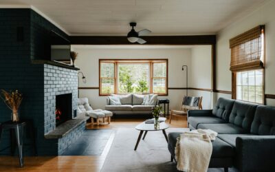 Modern living room with gray sofas, a wooden coffee table, and a cozy fireplace, featuring large windows that allow natural light, emphasizing the importance of maintaining a clean and inviting home environment.