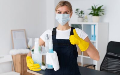 Person in a mask and yellow gloves holding cleaning supplies, showcasing office cleaning readiness, emphasizing hygiene and maintenance in a workspace.