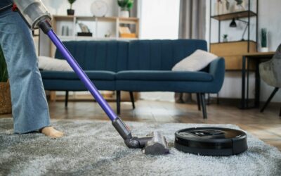Person vacuuming a plush area rug with a modern vacuum cleaner in a cozy living room setting, emphasizing home cleaning and maintenance.