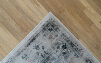 Corner of a decorative area rug on hardwood floor, emphasizing carpet care and maintenance in home cleaning.