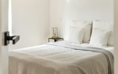 Cozy bedroom setting featuring a neatly made bed with white pillows and a light blanket, highlighting the importance of a clean mattress for health and sleep quality.