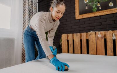 Woman in gloves cleaning a mattress, emphasizing stain removal techniques relevant to maintaining a fresh and comfortable bedroom environment.