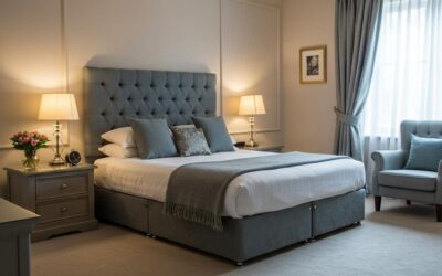 Elegant bedroom featuring a plush gray upholstered bed, decorative pillows, bedside lamps, and a cozy armchair, emphasizing the importance of a clean mattress for a healthier home.